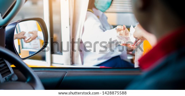 Selective focus to\
driver pay for the expressway. Man pays money to a cashier for a\
toll road toll gate motorway entrance. Hand paying express toll way\
on the road. pay express\
way.