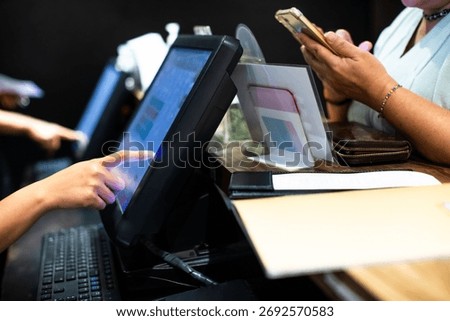 Selective focus to edge of POS machine with blurry cashier staff receive orders from customers at counter service in restaurant or cafe. Post of sale Concept.