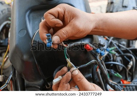 Selective focus electric bridge for separating wires in the hand of a car mechanic The car's electrical system is being repaired.