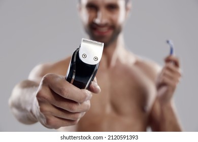 Selective Focus Of Electric Razor In Hand Of Blur Caucasian Man With Disposable Razor. Concept Of Face Care. Idea Of Male Beauty. Isolated On White Background. Studio Shoot