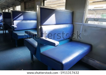 Selective focus empty blue seats of 3rd class train of Thailand. Windows background. Concept of seat texture, vintage train, public transportation, economy class, leather seat texture.