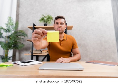 selective focus of empty sticky note in hand of freelancer sitting in home office