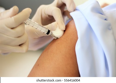A selective focus at the end of syringe while needle was injected into deltoid muscle and using the cotton to stop bleeding while pulling the needle out