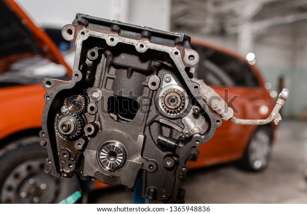 Selective focus. Engine Block on a\
repair stand with Piston and Connecting Rod of Automotive\
technology. Blurred car on background. Interior of a car repair\
shop.