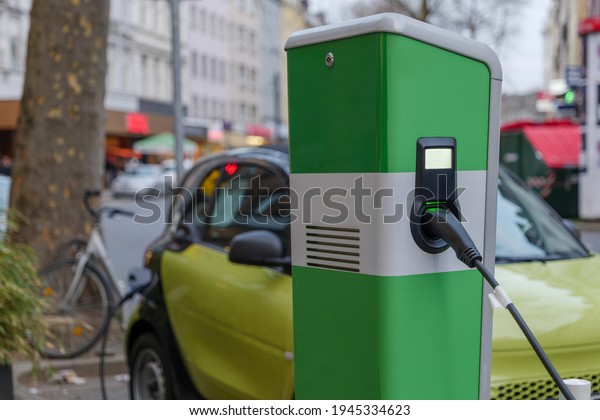 Selective focus,\
EV Electric Vehicle changing station on sidewalk beside car park on\
street in Düsseldorf, Germany.\
