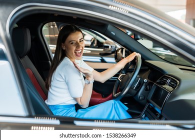 Selective Focus Of Excited Woman Waving Hand While Sitting In Car 