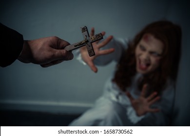 selective focus of exorcist holding cross in front of yelling obsessed girl - Shutterstock ID 1658730562