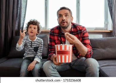 selective focus of father holding popcorn bucket near curly son pointing with finger while watching movie - Powered by Shutterstock