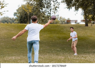 selective focus of father throwing rugby ball to teenager son in green park - Powered by Shutterstock