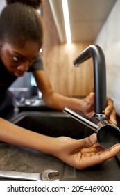 Selective Focus Female Hand Adjusting Kitchen Tap Handle. African Woman Plumber Holding Black Faucet, Fixing It. Modern Kitchen Amenities.