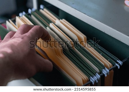 Selective focus filing cabinet looking three the files and folders, human hand
