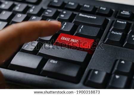 Selective focus of a finger and a red button computer keyboard written with Erase Past