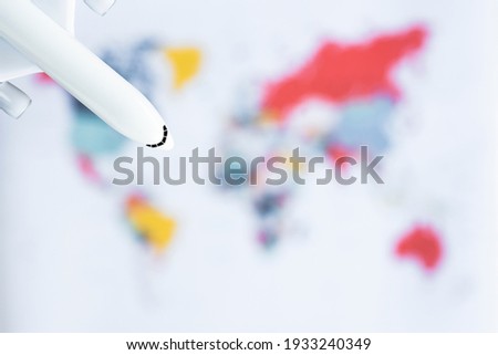 (Selective focus) Flat lay with copy space. Isolated white model aircraft on a blurred World Map. Travel concept during the Coronavirus, Covid-19 pandemic.