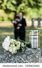 Selective Focus Of Flowers And Mortuary Urn On Tombstone