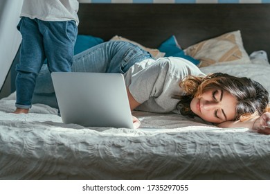 selective focus of freelancer lying on bed near laptop and toddler son