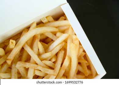 Selective Focus French Fries In A White Paper Box On A Black Background.