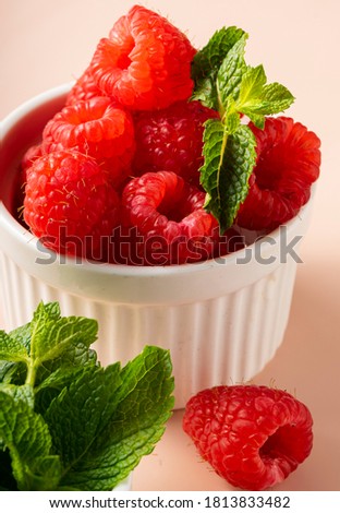 selective focus. fresh raspberries with a sprig of mint. in white fluted clay dishes on a soft pink background