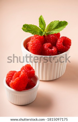 selective focus. fresh raspberries with a sprig of mint. in white fluted clay dishes on a soft pink background