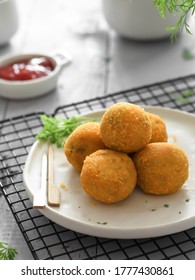 Selective focus of fried homemade Dutch Bitterballen with spicy sauce. Served in a white plate on a wire rack over blurry and noise white background.