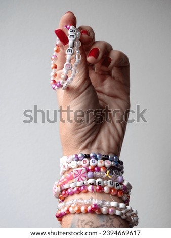 Selective focus. Friendship bracelets made of handmade plastic beads. Set of bright colorful braided bracelets with words. Colored ts teen jewelry.