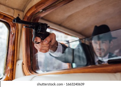 Selective Focus Of Gangster Aiming Gun With Outstretched Hand From Retro Car