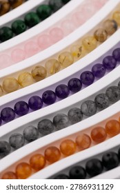 Selective focus gemstone bead strands in curved rows on white tray