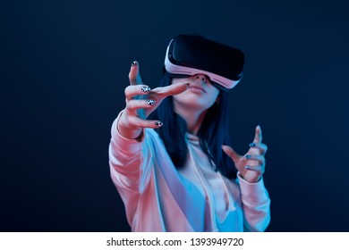 selective focus of girl wearing virtual reality headset and gesturing on blue  - Shutterstock ID 1393949720