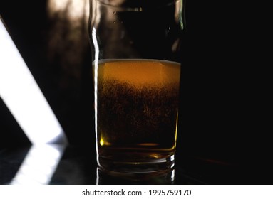 Selective Focus Of Glass Of Beer On The Bar Counter At Night Club. Nonic Pint Or Imperial Pint.  Alcohol Drinks. Half Empty Glass. Drinking Beer At Bar. Alcohol Drinks. Nightclub Life. Alcohol Abuse.