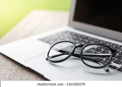 Selective focus of The glasses are on the laptop keyboard with warm light