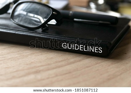 Selective focus of glasses, pen and black book title of Guidelines on wooden background.