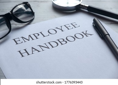 Selective Focus Of Glasses,magnifying Glass,pen And Paper Written With Employee Handbook On White Wooden Background.