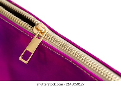 Selective focus, golden yellow metal zipper of a purple bag on a white isolated background. Some of the zipper teeth are closed. Close-up zipper background photo.