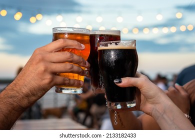 Selective Focus. Group Of Friends Toasting. Glasses Colliding In The Air. Toast. Glasses With Beer. Friends In A Bar. No People