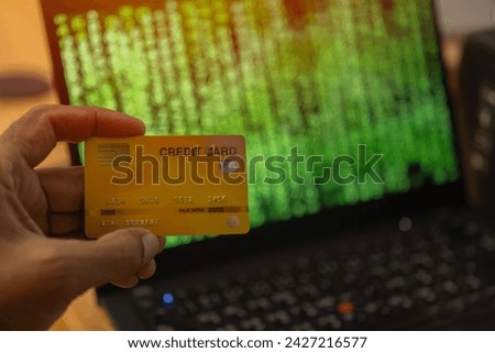 Selective focus of hacker hand holding a credit card and stolen data of online account. Payment Security Concept. 