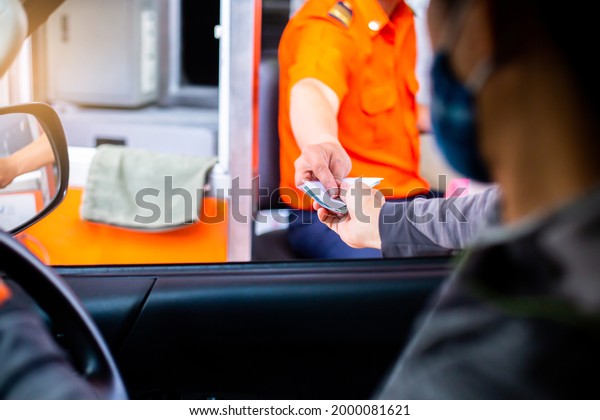 Selective\
focus to hand of driver pay for the expressway. Man pays money to a\
cashier for a toll road toll gate motorway entrance. Hand paying\
express toll way on the road. pay express\
way.
