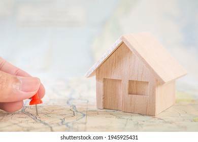 Selective focus of hand holding a pin and house model on map background for real estate concept - Shutterstock ID 1945925431