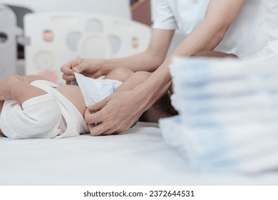 Selective focus hand of mother. Baby lying on bed is changing diaper by his mother. Baby healthcare hygiene concept. - Powered by Shutterstock