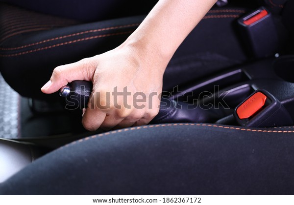 Selective focus, Hand\
pulling handbrake in the car. Closeup of young woman pulling\
handbrake lever in\
car.