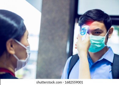 Selective Focus To Hand Of Staff Holding Digital Thermometer To Check Fever Visitor At Information Counter For Scan And Protect The Coronavirus (COVID-19). Screening Point For People Before Entering .