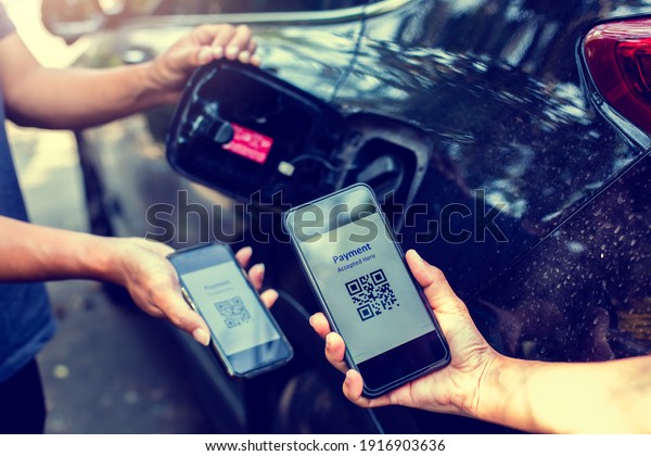Selective focus to Hand\
using smart phone to scan QR code tag with blurry fuel tank cap\
after refueling is complete. The customer is paying for the car\
fuel with QR code.