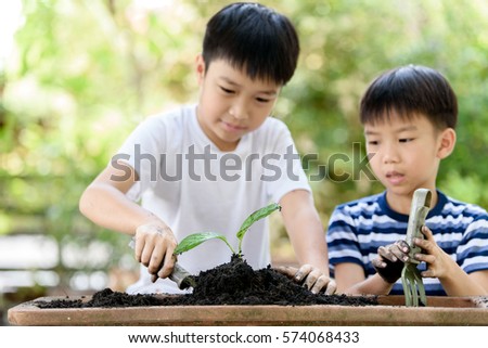 Selective focus at hand, Young Thai boy planting little seedling on the black soil in the garden. Earthday concept.