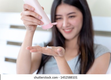 Selective Focus Hand's Beautiful Asian Woman Holding And Pour Skin Lotion From Pink Bottle Onto The Palm Of Her Hand, Healthcare Skin Concept