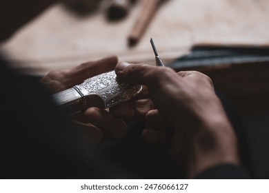 Selective focus. Hands of a dagger maker at work, close-up. Silver blade scabbard, handmade, the process of creation. Concept of individual engineering production. Kubachin jewelry masters