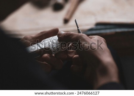 Selective focus. Hands of a dagger maker at work, close-up. Silver blade scabbard, handmade, the process of creation. Concept of individual engineering production. Kubachin jewelry masters