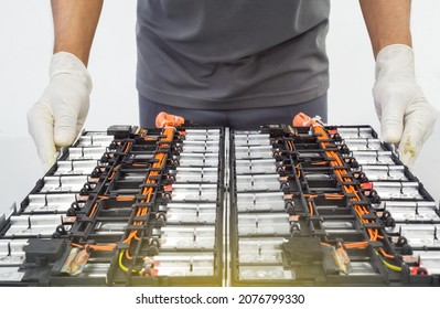Selective focus hands in gloves of expert technicain electric car, EV car while opened A used Lithium-ion car battery before its repair - Shutterstock ID 2076799330