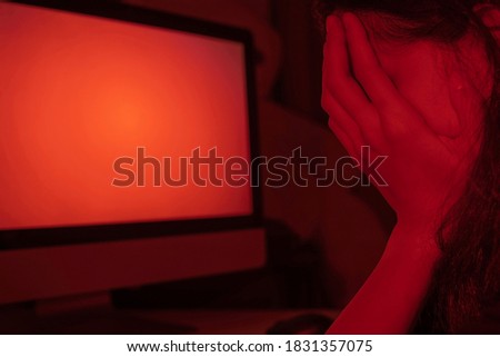Selective focus of hands of shamed face girl behind the computer monitor. Concept cyber bullying, cyber crime, cyber harassment. Copy space.