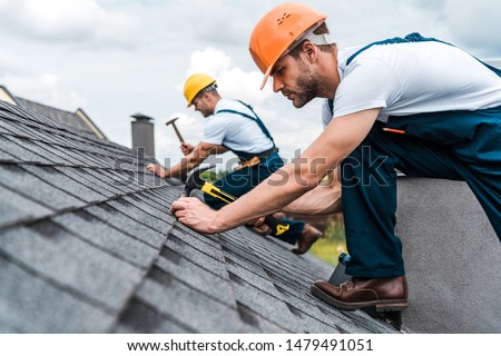 selective focus of handsome handyman repairing roof with coworker  Сток-фото © 