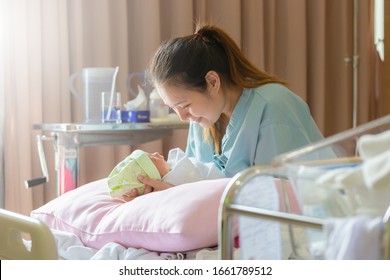 Selective Focus Of Happy Asian Mother Looking Newborn Baby Boy Sleeping In Hand At Hospital