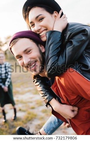 selective focus of happy coupe looking at camera while piggybacking together