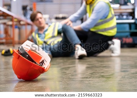 Selective focus at hat, Men worker feel painful and hurt from the accident that happen inside of industrial factory while his co-worker come to give emergency assistance and help. Accident in factory.